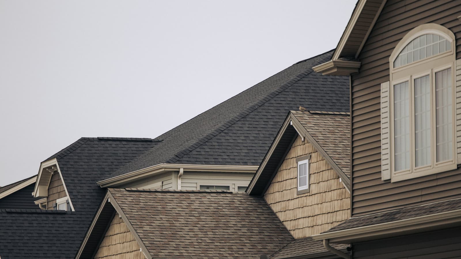 Rooflines of suburban houses with dark and brown architectural asphalt shingles