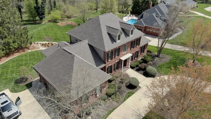 Aerial view of large brick home with new gray roof